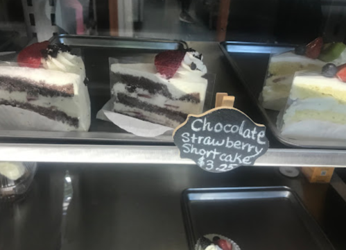 Slices of chocolate and strawberry shortcake displayed in a glass case, with a price tag of $3.25.