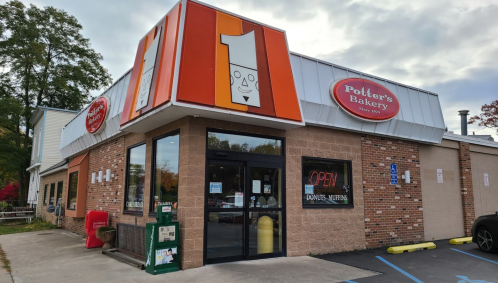 Exterior of Potter's Bakery with a large sign, open door, and colorful landscaping in front.