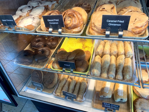 A display case filled with various pastries, including cinnamon rolls, glazed fried cinnamon, and cream-filled treats.