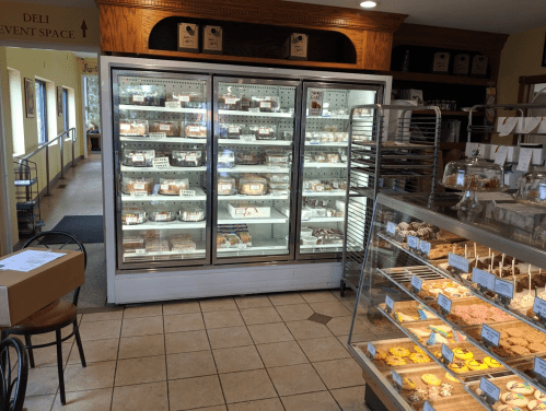 A bakery display featuring a glass case with assorted pastries and a refrigerated section filled with desserts.