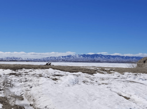 A snowy landscape with mountains in the background under a clear blue sky.