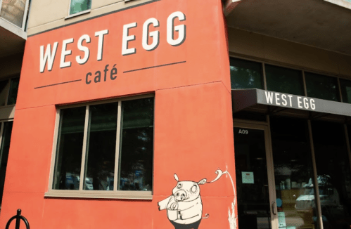 Exterior of West Egg Café featuring a bright red wall and a cartoon pig illustration near the entrance.