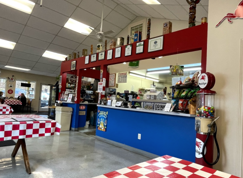 Interior of a casual diner with red and white checkered tables, a colorful counter, and various decorations on the walls.