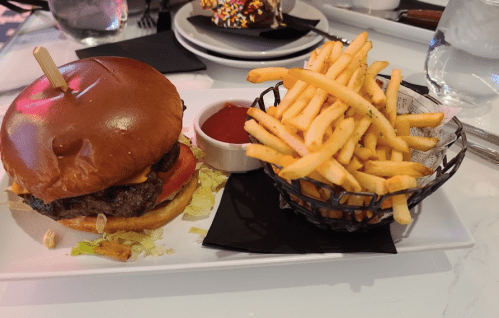 A juicy burger with lettuce and tomato, served with a side of crispy fries and ketchup on a white plate.