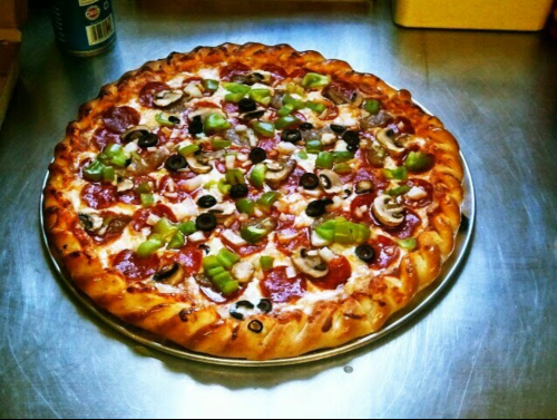 A freshly baked pizza topped with pepperoni, mushrooms, green peppers, and black olives on a golden crust.
