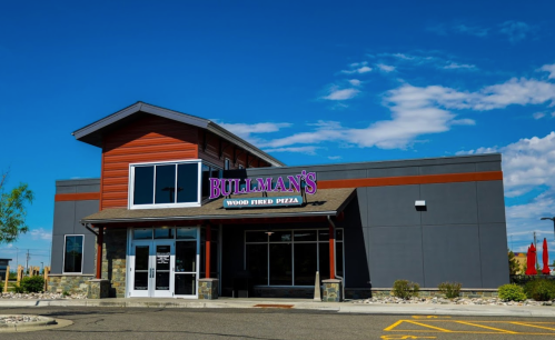 Exterior of Bullman's Wood Fired Pizza restaurant, featuring a modern design and clear blue sky.