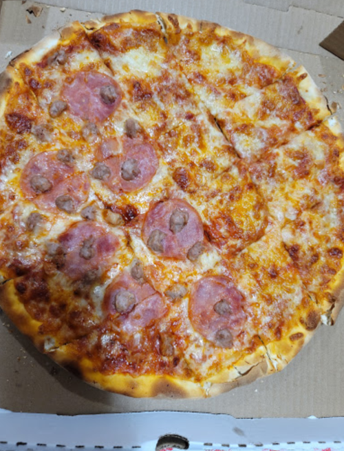 A large pizza with melted cheese and slices of ham, in a cardboard pizza box.