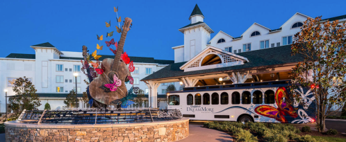 A colorful butterfly sculpture and a trolley in front of a hotel at dusk.
