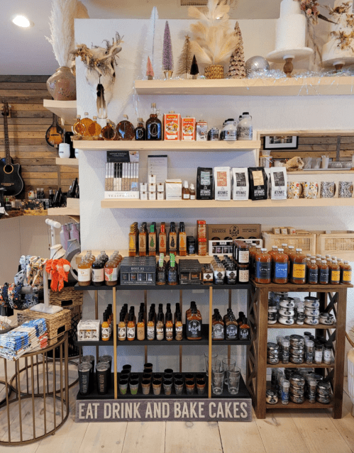 A cozy shop display featuring shelves of gourmet food items, drinks, and baking supplies, with decorative accents.