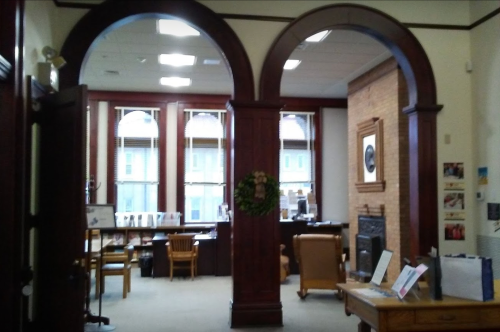 Interior view of a room with arched doorways, wooden furniture, and large windows, creating a warm, inviting atmosphere.