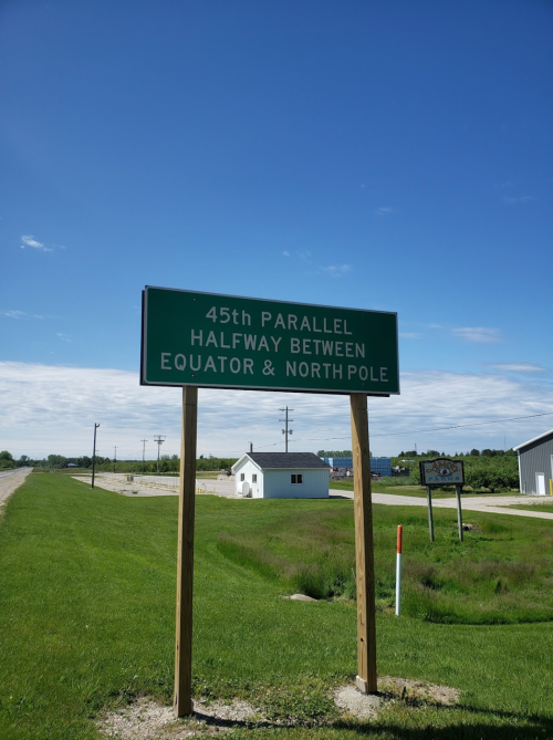 Sign indicating the 45th parallel, halfway between the Equator and North Pole, with a clear blue sky in the background.