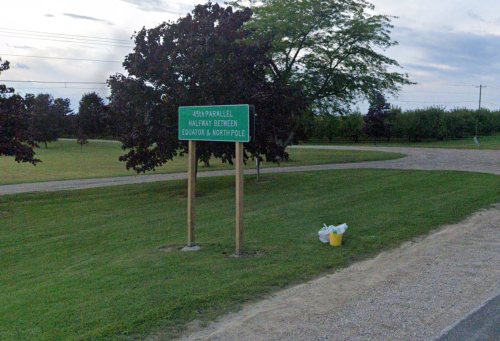 Sign marking the 45th parallel, halfway between the Equator and the North Pole, in a grassy area.