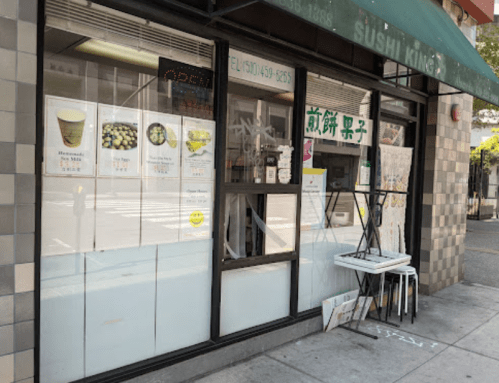 Exterior of Sushi King restaurant with a menu displayed in the window and outdoor seating.