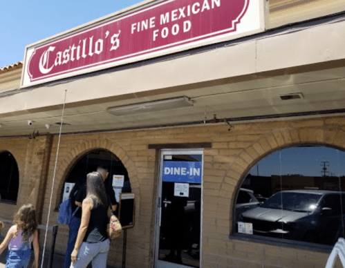 A woman and a child approach the entrance of Castillo's Fine Mexican Food, featuring a dine-in sign.