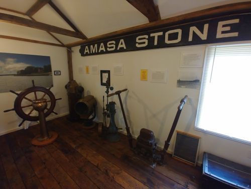 A museum display featuring maritime artifacts, including a ship's wheel and various historical equipment.