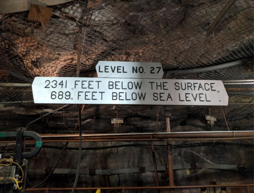 Sign indicating "Level No. 27: 2341 feet below the surface, 689 feet below sea level" in a mine.