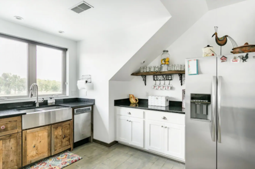 Bright kitchen with a stainless steel sink, white cabinets, and a cozy rug, featuring modern appliances and natural light.
