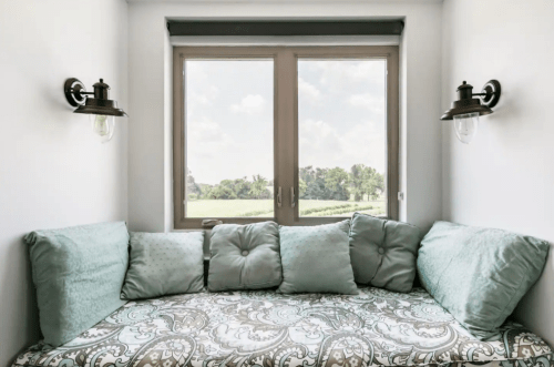 Cozy window nook with plush cushions and a scenic view of greenery outside.