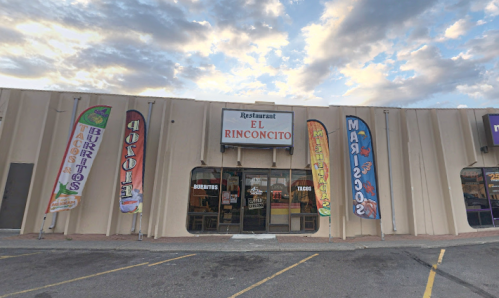 Exterior of El Rinconcito restaurant with colorful banners advertising tacos and burritos under a cloudy sky.