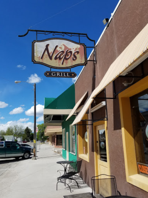 Sign for Nap's Grill on a sunny day, with a brown building and outdoor seating visible.