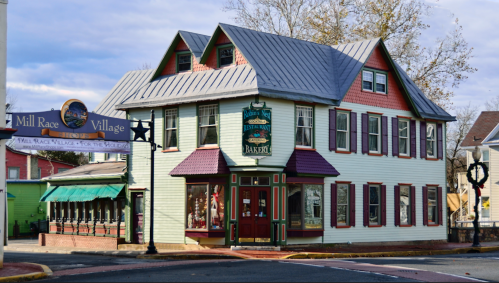 Charming multi-colored building with a bakery sign, located in Mill Race Village, featuring a welcoming outdoor dining area.