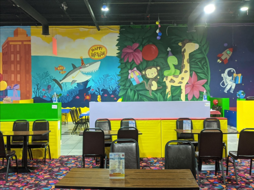 Colorful children's party venue with a vibrant mural, tables, and playful decorations.