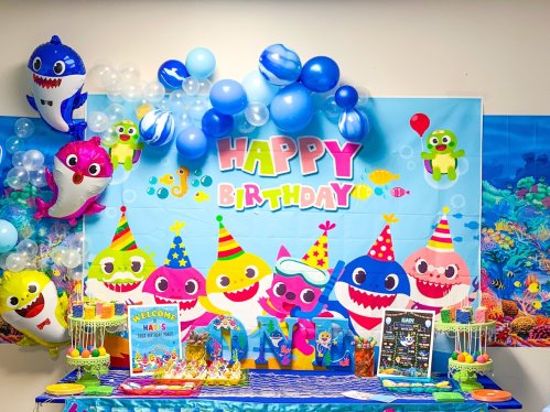 Colorful birthday party setup featuring a "Happy Birthday" banner, balloons, and decorations with cartoon sea creatures.