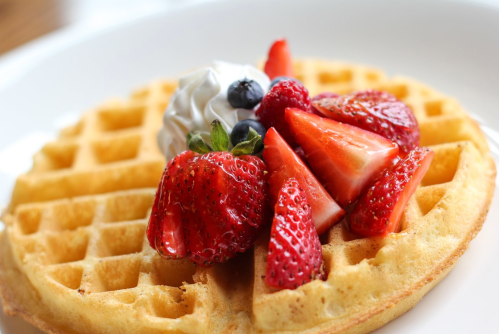 A golden waffle topped with whipped cream and fresh strawberries and blueberries.