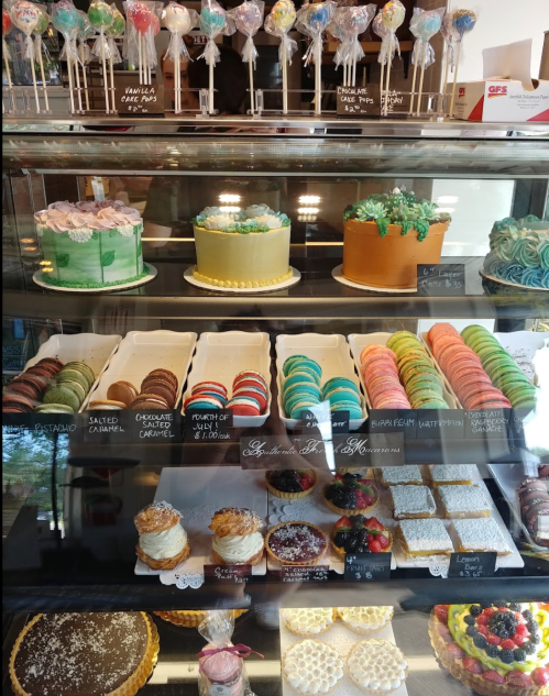 A display case filled with various colorful cakes, cookies, and desserts, including cupcakes and cake pops.