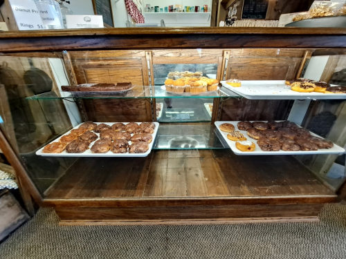 A wooden display case filled with various baked goods, including cookies, muffins, and pastries.