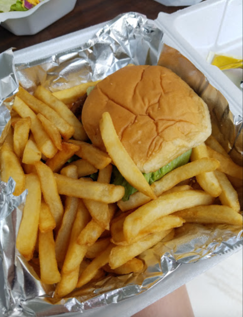 A foil container with a burger and a generous serving of golden French fries.