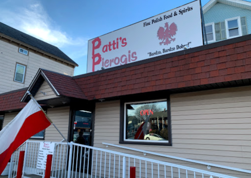 Sign for Patti's Pierogis, a Polish restaurant, with a red and white flag in front and an "OPEN" sign in the window.