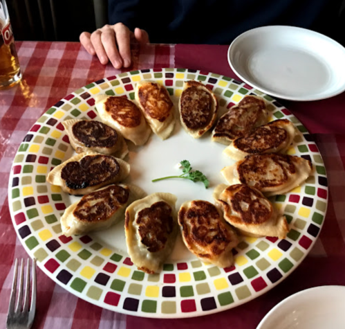 A colorful plate of dumplings arranged in a circle, with a small green garnish in the center.