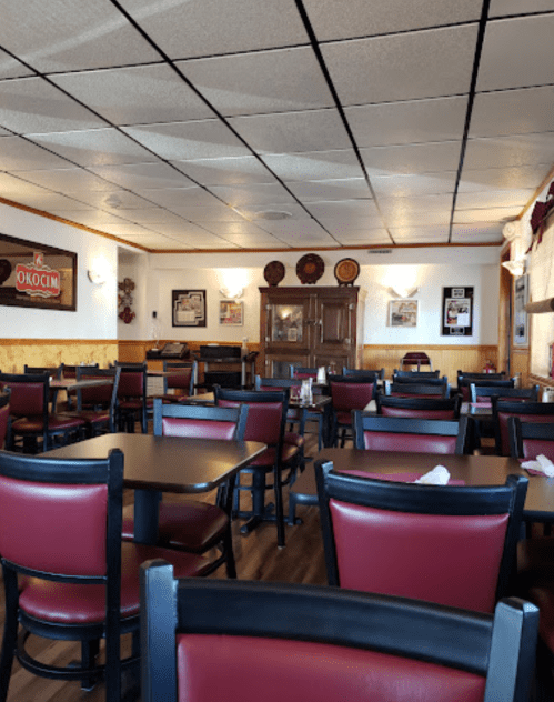 A nearly empty restaurant with red and black chairs, wooden tables, and a cozy, inviting atmosphere.