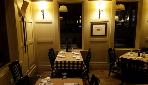Cozy restaurant interior with checkered tablecloths, wooden chairs, and warm lighting.