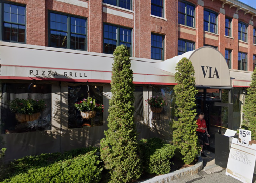 Exterior of a restaurant named "Via" with a sign for "Pizza Grill," surrounded by greenery and a valet parking sign.