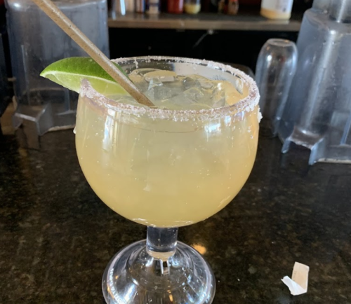 A refreshing margarita in a glass with a salted rim, garnished with a lime wedge and served over ice.