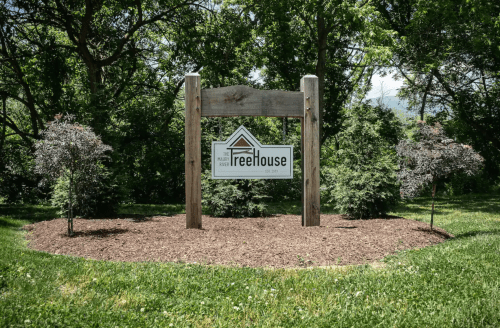 Sign for "FreeHouse" surrounded by greenery and small trees, set in a landscaped area.