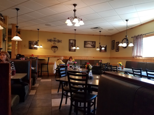 Cozy restaurant interior with booths, tables, and warm lighting; patrons enjoying meals amidst floral centerpieces.