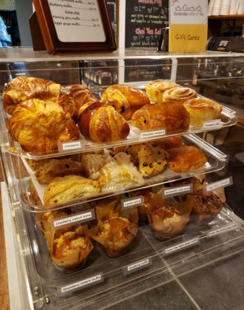 A display case filled with various baked goods, including croissants, muffins, and pastries.