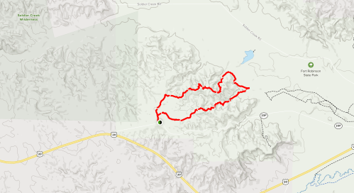 Map showing a winding red trail through mountainous terrain, with nearby roads and a lake indicated.
