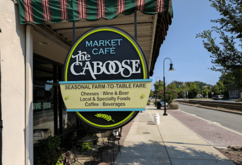 Sign for "The Caboose" Market Café, featuring seasonal farm-to-table fare, cheeses, wine, beer, and local foods.