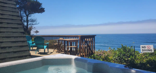 A hot tub overlooks a scenic ocean view with blue skies, a wooden deck, and a "No Diving" sign nearby.