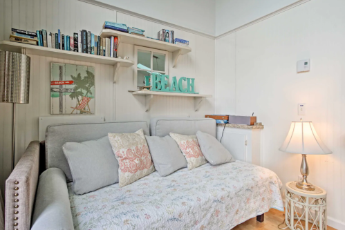 Cozy living space with a light gray sofa, decorative pillows, bookshelves, and beach-themed decor.