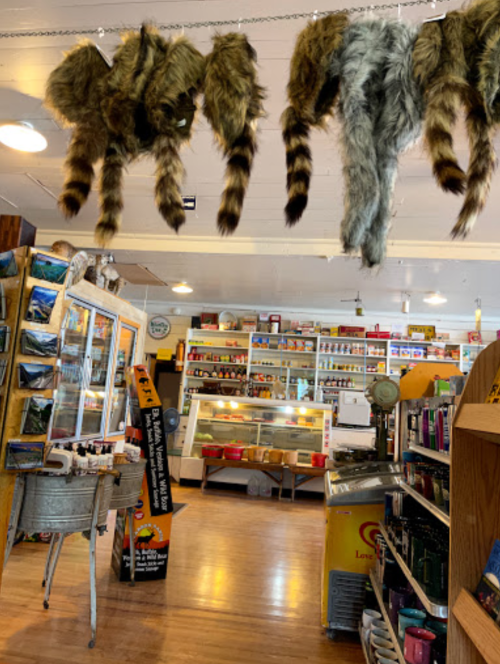A store interior featuring hanging faux animal tails and various products on shelves, with a display case in the background.