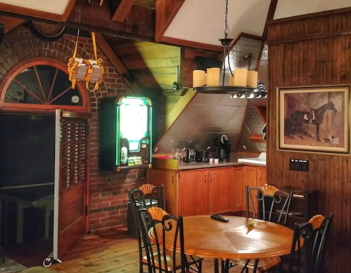 Cozy interior of a rustic kitchen with wooden accents, a round table, and a vintage jukebox in the corner.