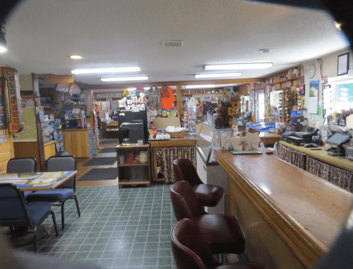 A cozy diner interior with a counter, seating, and colorful decor, featuring a variety of items on display.
