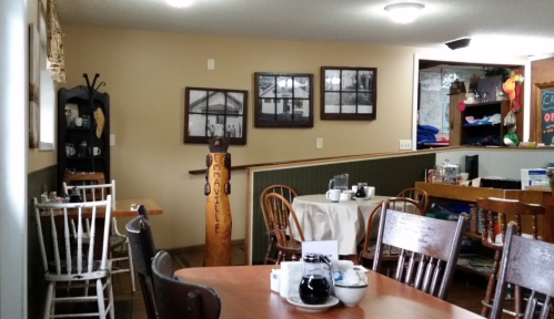 Cozy café interior with wooden tables, chairs, and framed photos on the walls, creating a warm atmosphere.