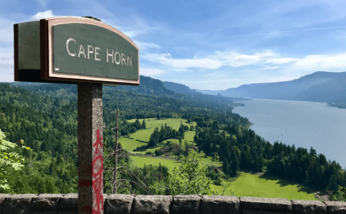 Sign for Cape Horn overlooking a lush green landscape and river under a clear blue sky.