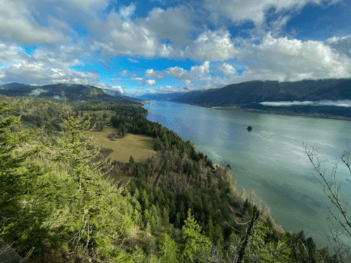 A scenic view of a river winding through lush green hills under a partly cloudy sky.